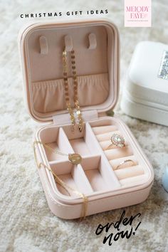 an open jewelry box on the floor with rings and necklaces in it, next to a white case