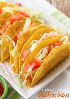 several tacos on a white plate with salsa and ketchup