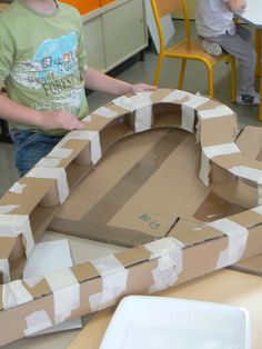 two young boys are making a cardboard castle