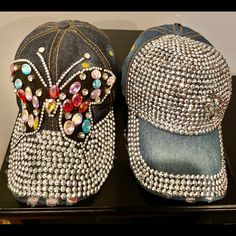 two hats with beading on them are sitting on a black table and one has a blue hat with beads