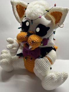 a crocheted stuffed animal holding an orange and white teddy bear in its arms