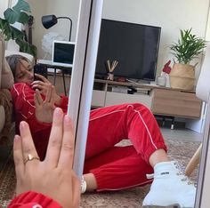 a woman in red pajamas taking a selfie with her cell phone while sitting on the floor