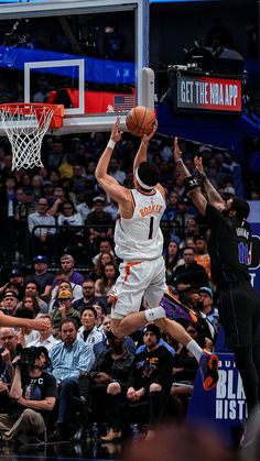 a basketball player jumping up to dunk the ball in front of an audience at a game