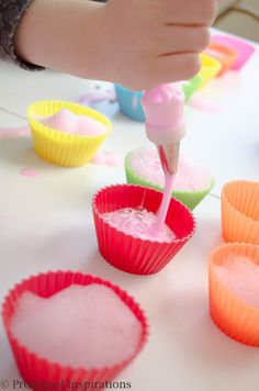 someone is decorating cupcakes with pink icing