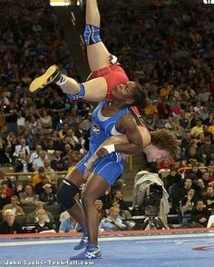 two people doing tricks in front of an audience at a wrestling match with spectators watching