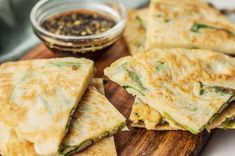 several quesadillas on a cutting board with dipping sauce