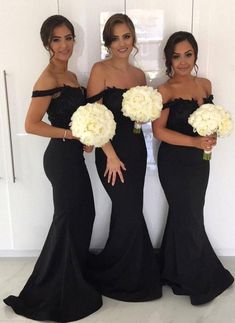 three women in black dresses standing next to each other with bouquets on their chests