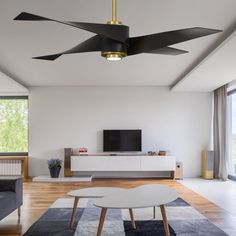 a modern living room with white walls and wood flooring, black ceiling fan, large tv on the wall