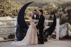 a man and woman standing next to each other in front of a moon shaped sculpture