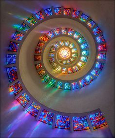 a spiral stained glass window in the center of a room with many windows on it