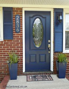 a blue front door with two planters on it