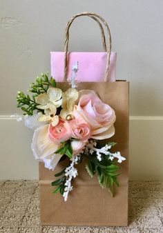 a brown paper bag with pink and white flowers in it sitting on the floor next to a wall