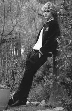 black and white photograph of a man leaning against a tree