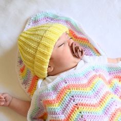 a baby wearing a crochet hat laying on top of a blanket