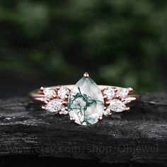 a green and white stone ring sitting on top of a piece of wood with trees in the background