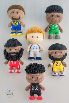 crocheted dolls of soccer players are arranged in a row on a white surface