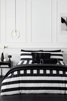 a bed with black and white comforter in a room next to two pictures on the wall