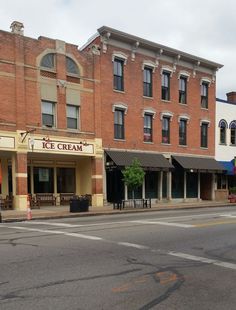 an old brick building on the corner of a street in front of a cafe and ice cream shop