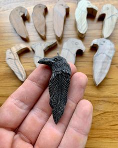 a hand holding a small black bird on top of a wooden table next to other pieces of wood