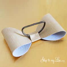 a close up of a bow tie on a wooden table with a metal hook attached to it