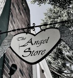 the angel store sign is hanging from a wire near a brick wall and tree branches