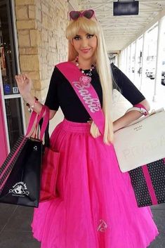 a woman with long blonde hair wearing a pink skirt and black top