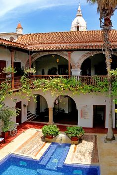 an outdoor swimming pool in the middle of a courtyard with potted plants on either side