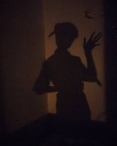 the shadow of a person's head on a wall with their hands in the air