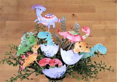 a vase filled with lots of different types of paper animals on top of a wooden floor