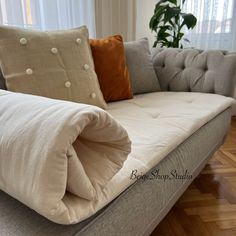 a couch with two pillows on it and a blanket folded over the back of it