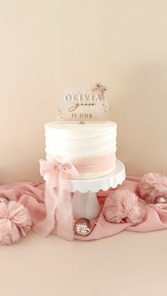 there is a wedding cake on the table with pink pom - poms around it