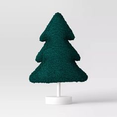 a small green christmas tree on a white stand