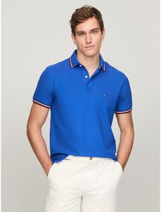 Tommy Hilfiger men's polo. A fresh spin on tradition, this regular-fit polo is made from quick-dry, wicking fabric with ultraviolet protection and features our signature stripe tipping at the cuffs and collar. Comfort? Check. Performance? Style? Check.  Material: 60% Regenerative Cotton, 40% Polyester Pes. Classic Blue Polo Shirt With Contrast Stripes, Blue Cotton Polo Shirt With Three Stripes, Blue Sporty Polo Shirt With Ribbed Collar, Classic Navy Polo Shirt With Contrast Trim, Classic Three-stripes Polo Shirt, Classic Three Stripes Polo Shirt, Sporty Blue Polo Shirt With Contrast Stripes, Classic Polo Shirt With Striped Collar For Golf, Golf Polo Shirt With Three Stripes