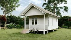 a small white house sitting on top of a lush green field