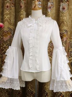 Features: It features lace ruffled collar, long trumpet sleeves, multi-layer lace ruffled and bowknot decortaion on the sleeves, placket with five buttons, elegant shirt.Attention: This price includes a shirt only, others are not included. Size Chart: Size (CM): Unit CM; Sizes below are measured in flat-laid position, hand measurement will have discrepancy of about 2 CM.Size(cm)SMLXLXXLShoulders3536383940Bust84889296100Waist7074788286Sleeve Length5960616263Shirt Length5657585960 Fitted White Blouse With Bow, Elegant Bell Sleeve Blouse, Elegant Bell Sleeve Party Blouse, White Long Sleeve Blouse With Bow, White Doll Collar Blouse For Party, Elegant Tops With Lace Trim And Ruffle Sleeves, Elegant Party Blouse With Lace Cuffs, Feminine Ruffled Bell Sleeve Blouse, Fitted Lace Blouse With Ruffles