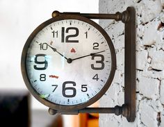 a clock is hanging on the side of a brick wall in front of a window