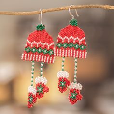 two christmas themed beaded earrings hanging from a tree branch