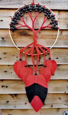 a red and black dream catcher hanging on a wooden wall