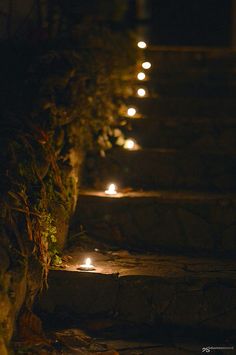 lighted steps leading up to the top of a hill at night with lit candles on them