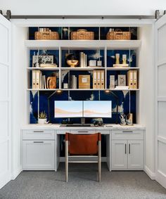 a home office with built - in shelving and desks, including a computer