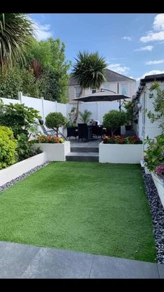 an outdoor area with grass and plants on the ground, surrounded by white fenced walls