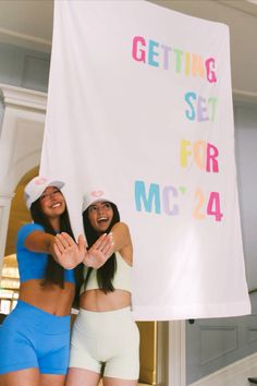 two women standing next to each other in front of a sign that says getting set for mc'24