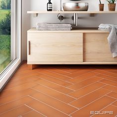 a bathroom with an orange tile floor and white walls, along with a wooden cabinet that has towels on it