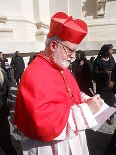 a man dressed in red and white writing on a piece of paper while standing next to other people