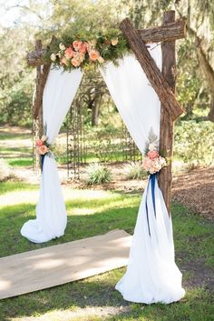 an outdoor wedding ceremony setup with white drapes and flowers on the arch, along with blue ribbon