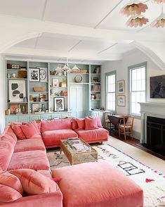 a living room filled with pink couches next to a fire place in front of a fireplace