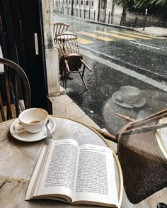 an open book sitting on top of a table next to a cup and saucer