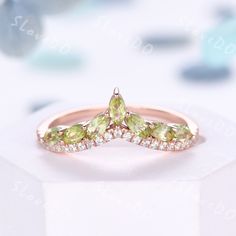 an image of a diamond ring with green stones on the side and diamonds in the middle