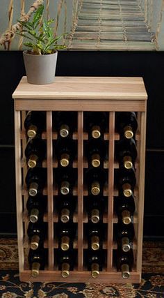 a wooden wine rack with many bottles in it and a potted plant on top