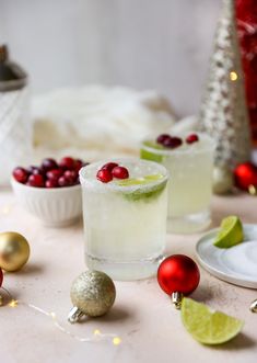 two glasses filled with drinks sitting on top of a table next to christmas decorations and ornaments